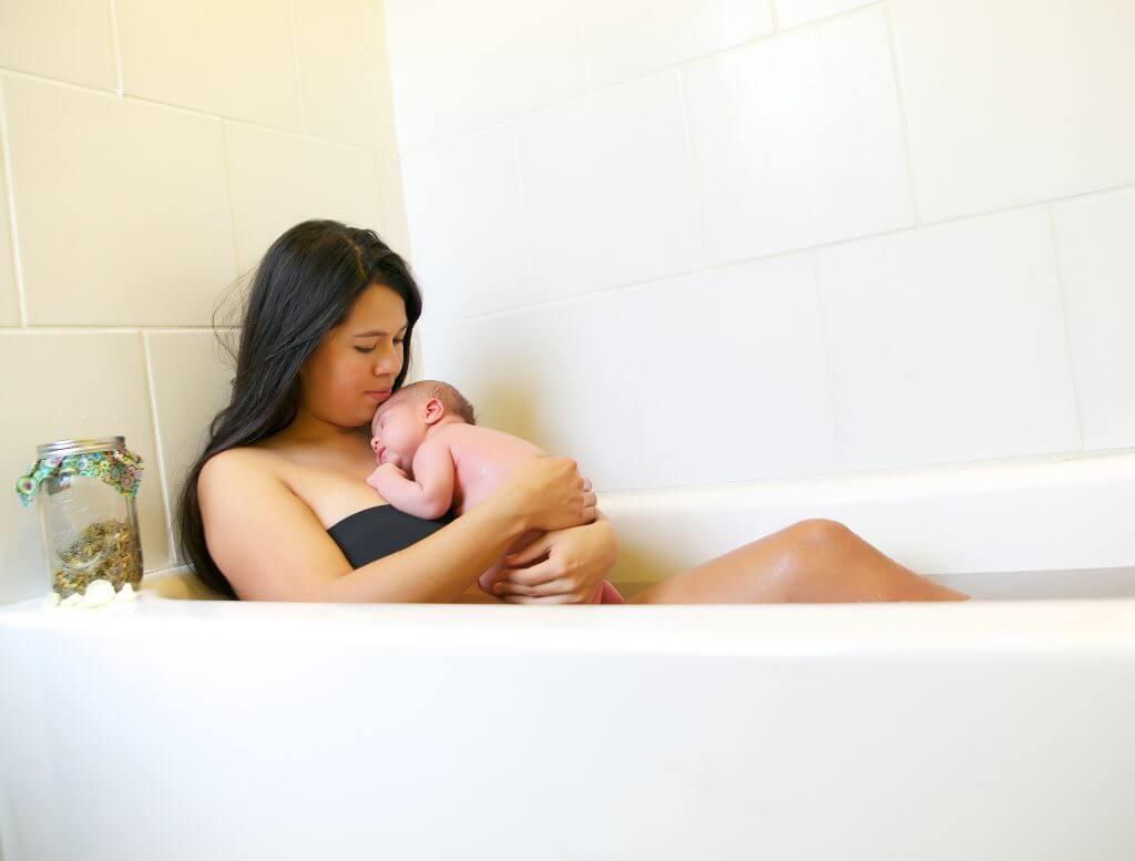 Mother holding baby in bathtub