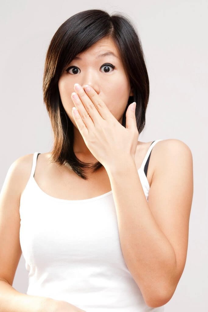 Surprised woman covers mouth with hand.