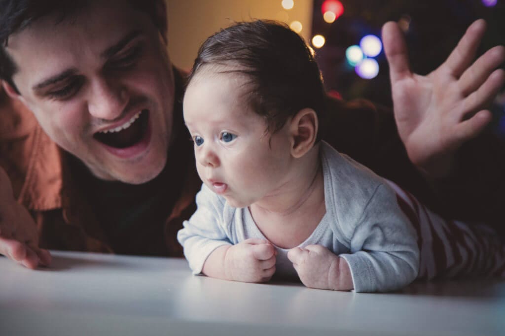 Smiling person with adorable baby on table.