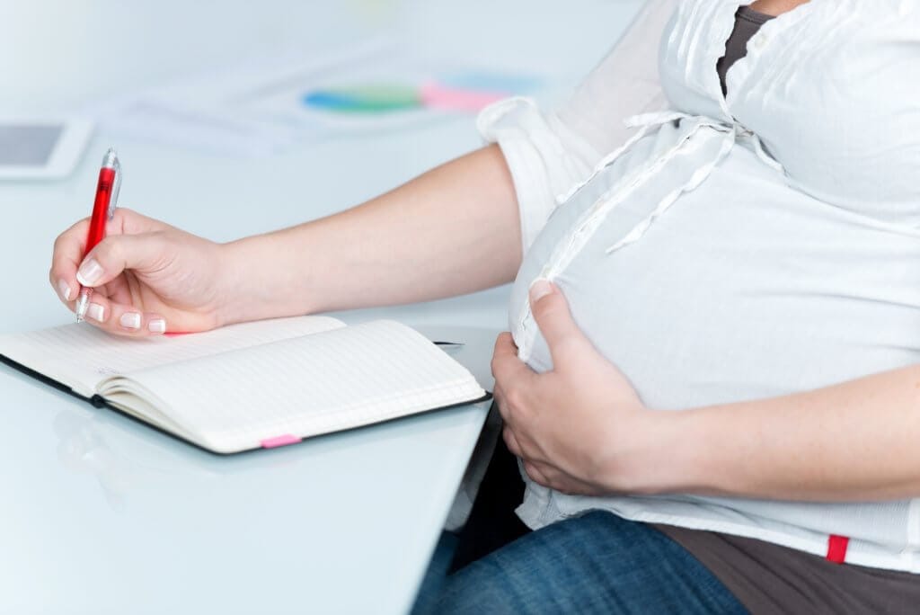 Pregnant woman writing in notebook.