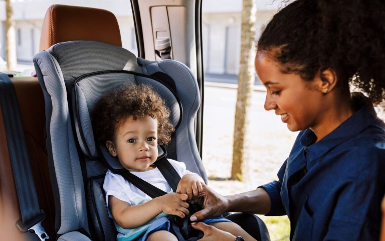 mom putting toddler in car seat