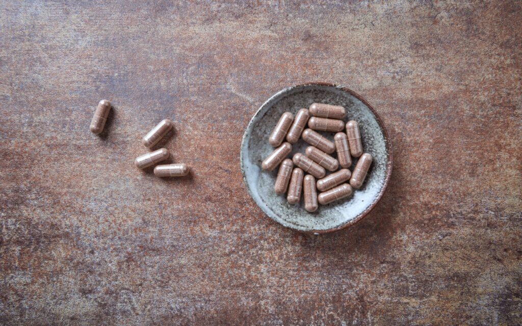 Placenta capsules in a jar on a wooden background. How much does placenta encapsulation cost in San Antonio