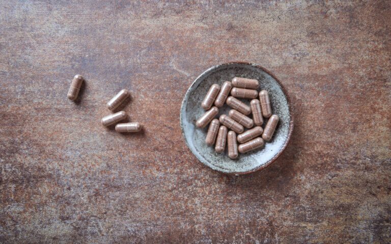 Placenta capsules in a jar on a wooden background. How much does placenta encapsulation cost in San Antonio