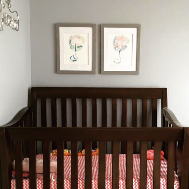 Two placenta prints displayed on a wall behind a crib.